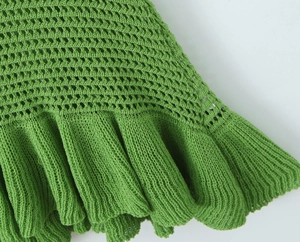 Dettaglio dell'abito in maglia verde con uncinetto traforato e orlo con volant