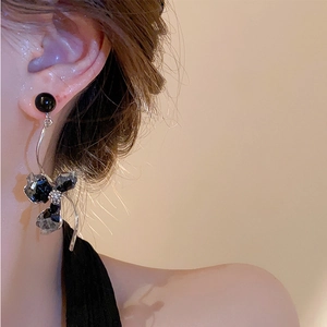 Close-up of asymmetrical crystal flower drop earring on model with silver metal rod
