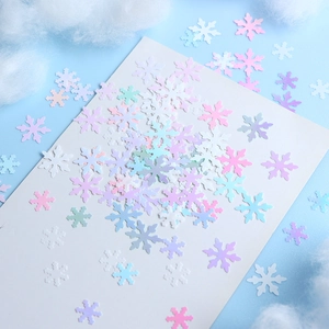 Detailed view of mixed pastel holographic snowflake nail sequins on a soft winter cloud background