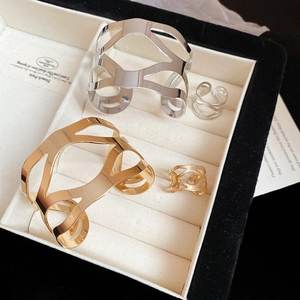 Detailed close-up of hollow geometric gold and silver bangles with matching rings in a gift box