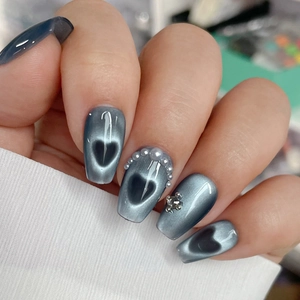 Detail of gray-blue cat eye nails with a 3D silver bear and pearl heart border decoration