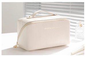 Detailed view of the vertical stripe texture and gold lettering on cream makeup bag