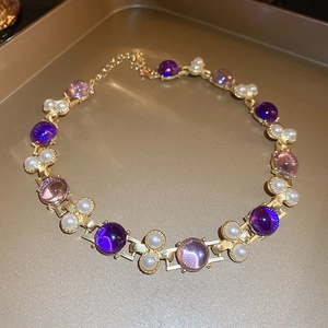 Vue macro du collier de perles dorées avec pierres violettes et fermoir mousqueton