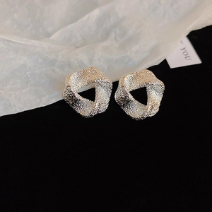 Macro shot of silver textured earrings with irregular twisted geometric design on velvet