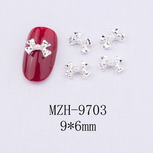 Bijou d'ongle nœud argenté avec perle blanche 9x6mm sur une manucure rouge vive