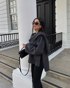 Detail of a dark gray knit shawl-style short jacket in a chic street style outfit