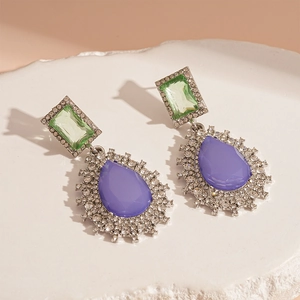 Macro shot of vintage teardrop earrings with lilac purple crystal and green gemstone