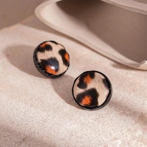 Minimalist round leopard print stud earrings with black metal trim on stone surface