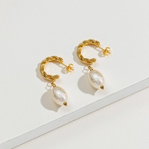 Dettaglio degli orecchini a cerchio intrecciati in oro 14k con eleganti perle bianche