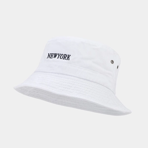 Detailed close-up of white cotton bucket hat with black New York embroidery and metal eyelets