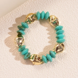 Close-up of turquoise irregular acrylic beads and gold metal accents on stone background