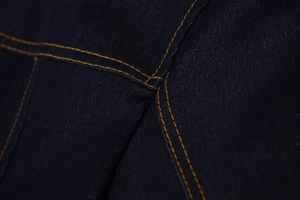Détail du tissu denim indigo haute densité avec coutures contrastées orange de qualité