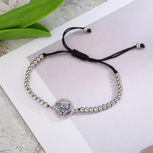 Détail d'un bracelet perlé réglable avec pendentif cœur orné de zircons multicolores