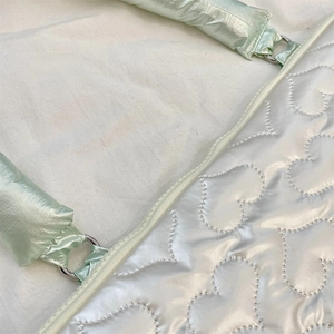Macro detail of heart quilted pearl silver laptop sleeve with mint green handle
