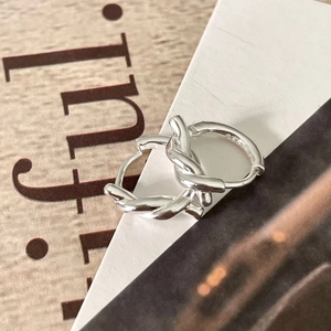 Macro view of knotted S925 sterling silver hoop earrings on a modern printed background