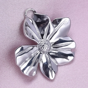 Macro shot of silver 304 stainless steel flower pendant on pink silk fabric background