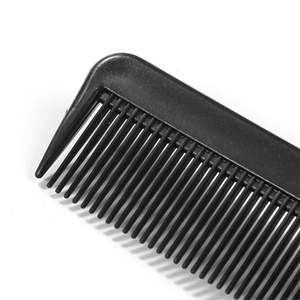 Dettaglio del pettine nero in plastica per meches con denti fitti su sfondo bianco