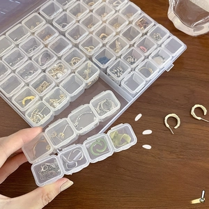 Detailed top view of 28-compartment clear jewelry storage box on a wooden desk