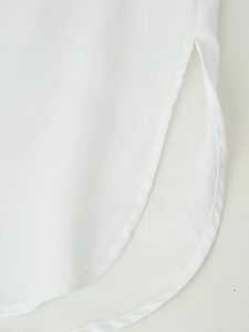 Close-up of side slit detail and breathable cotton linen texture on white top