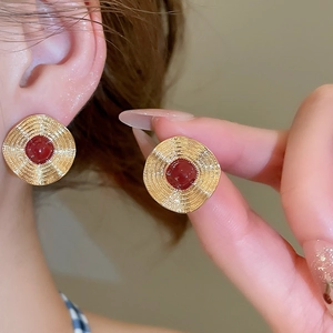 Makroansicht der goldenen Spiral-Ohrringe mit rundem rotem Stein im Vintage-Stil