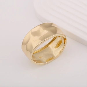 Macro shot of wide gold hammered metal cuff bracelet with a hinged closure