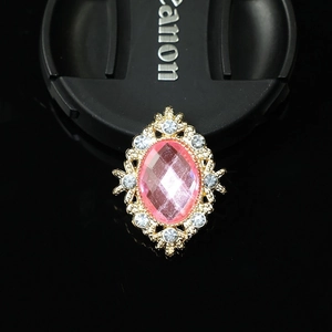 Macro shot of oval pink gemstone brooch with golden filigree and crystal accents