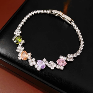 Macro detail of silver bracelet with colorful oval zircons on black leather background