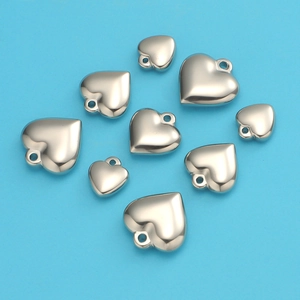 Detailed view of polished stainless steel heart charms in various sizes on blue background