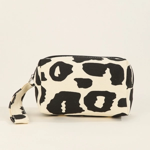 Canvas makeup bag featuring black and white cow print with zipper and handle strap