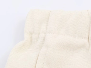 Vista macro dell'elastico in vita e trama a maglia dei pantaloni beige a vita alta