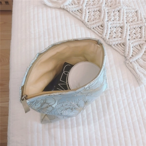 Detail of rose floral jacquard makeup bag with gold thread and metal zipper storage space