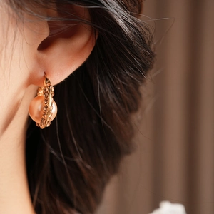Close-up of French vintage U-shaped earring with pink pearl and sparkling diamonds