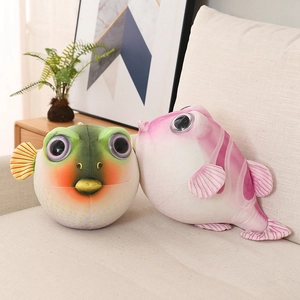 Détail de peluches poissons-globes ronds en vert et rose sur un canapé