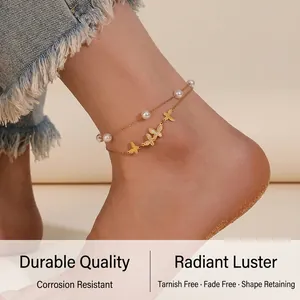 Detailed view of a gold double-layer butterfly anklet with pearls on a beach background