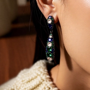 Close-up of vintage style silver drop earrings with blue and green zircon on a model