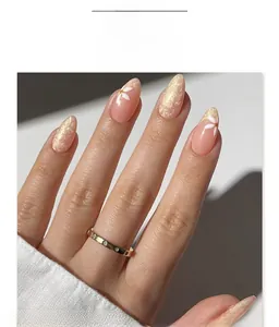 Detail of almond-shaped nails with white flower designs and sparkling gold foil accents
