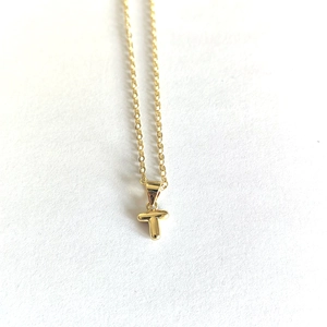 Detailed view of a minimalist gold necklace with a delicate letter T pendant on white paper
