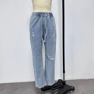 Dettaglio jeans azzurri strappati sulle ginocchia con vita elastica e coulisse regolabile