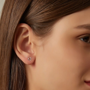 Minimalist silver heart stud earrings shown on model ear for elegant jewelry styling