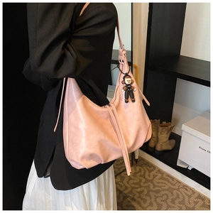 Detailed view of large pink soft leather shoulder bag with a cute doll charm accessory