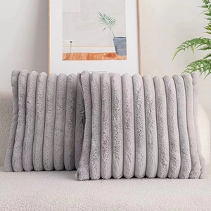 Detail of grey faux rabbit fur pillow cases with vertical stripes on a sofa
