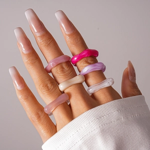 Détail de bagues en résine colorée avec texture marbrée sur main aux ongles dégradés