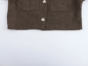 Gros plan sur l'ourlet d'une veste en tweed marron avec des boutons métalliques