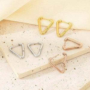Triangle geometric hoop earrings in gold, silver and rose gold finish on stone surface