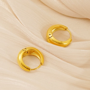 Detail view of 18k gold plated chunky hoop earrings on smooth silk fabric background