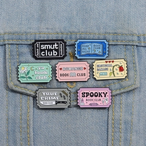 Set of 7 colorful bookish enamel pins with movie ticket designs on denim jacket pocket