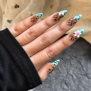 Detailed view of handmade almond nails with 3D leopard print and floral bead accents