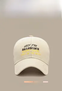 Detailed close-up of beige cotton baseball cap featuring 3D letter embroidery and curved brim
