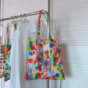 Détail d'un sac cabas en coton avec motifs de collage artistique sur un cintre argenté