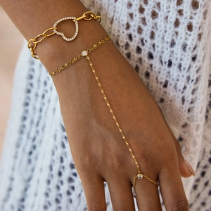 Gros plan d'un bracelet cœur doré avec strass et d'une chaîne de main multicouche